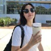 Chaelin Kim outdoors in sunglasses and a white top, holding a tumbler.