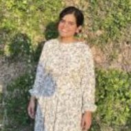 Syeda Mah Noor Asad in a floral dress, standing in front of greenery.