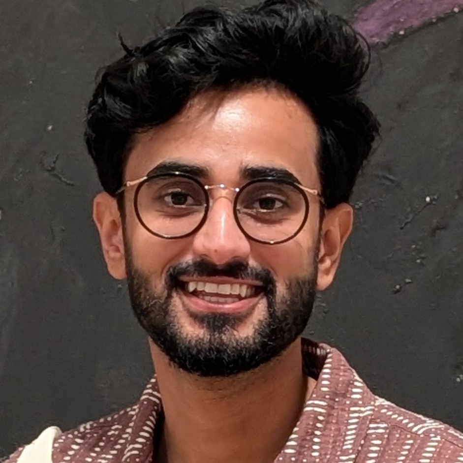 Saad Hassan is wearing a maroon shirt and black and golden glasses.