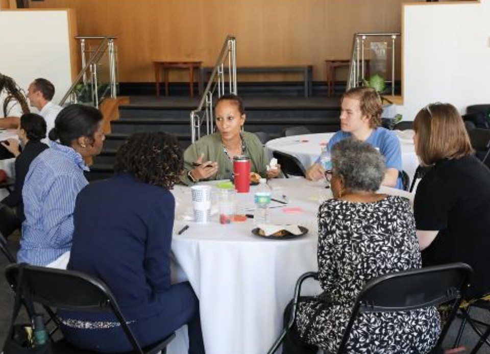 Community members and researchers talking around a round table at a workshop